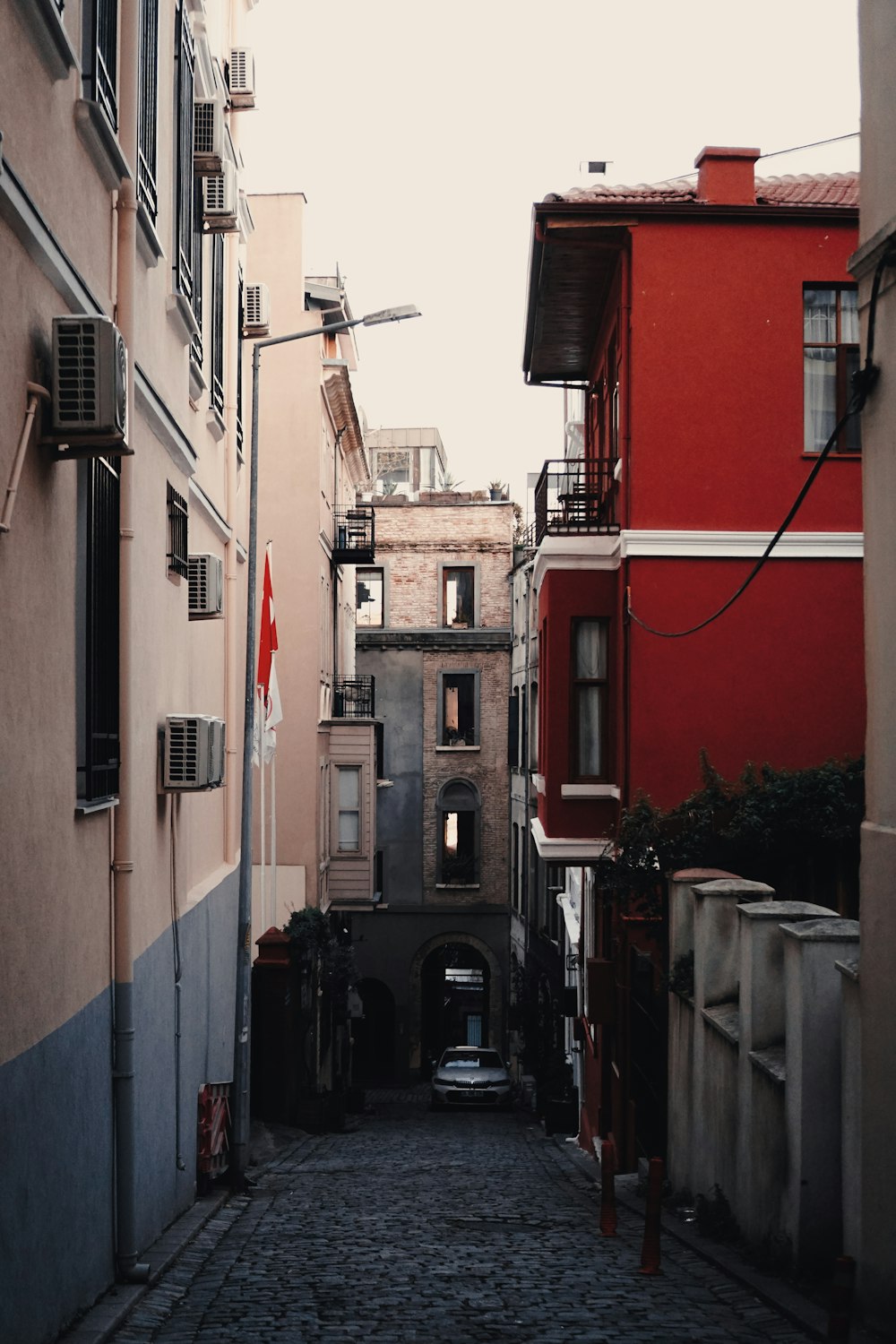 a narrow city street with a red building in the background