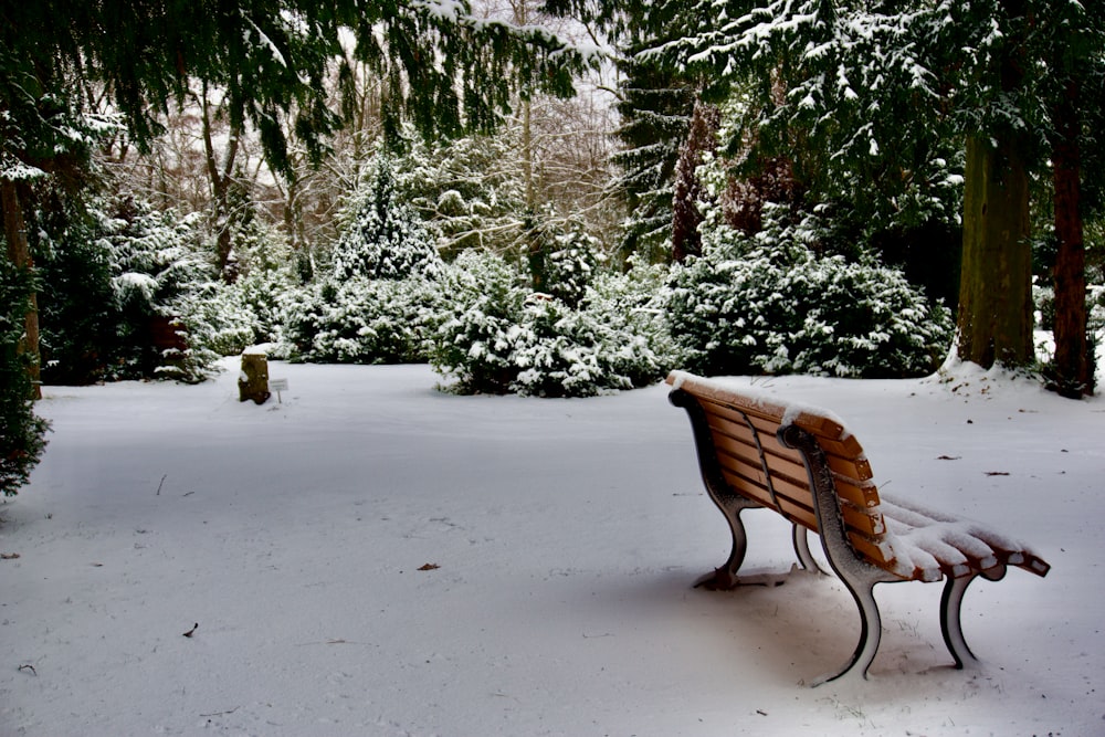 a wooden bench sitting in the middle of a snow covered park