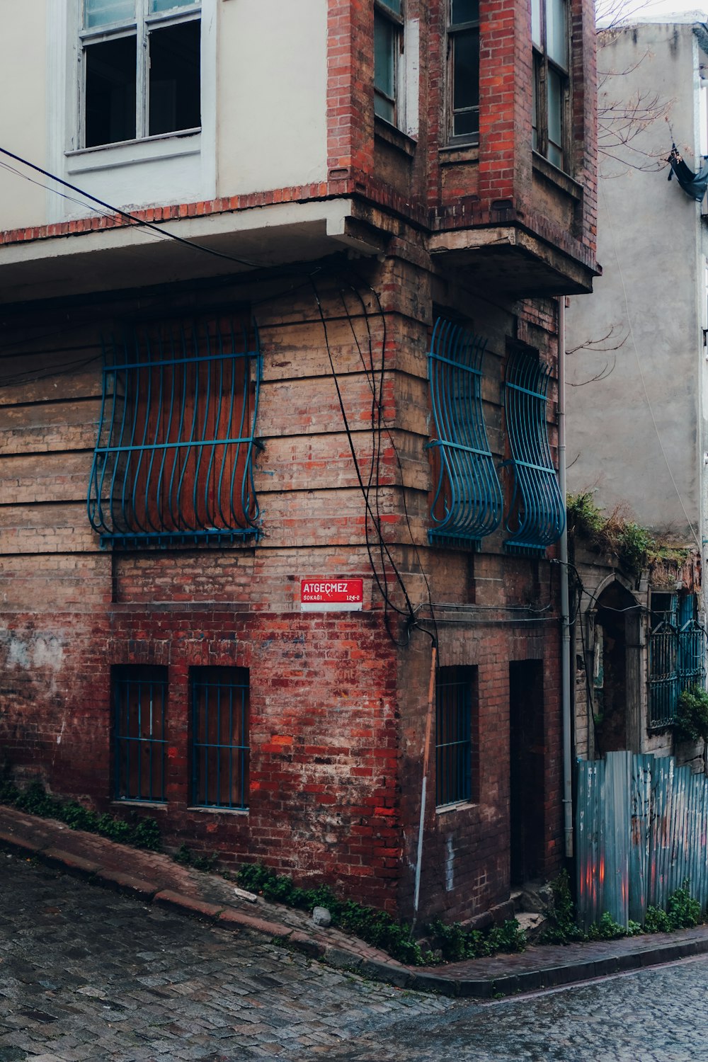 an old brick building with blue shutters and a red street sign