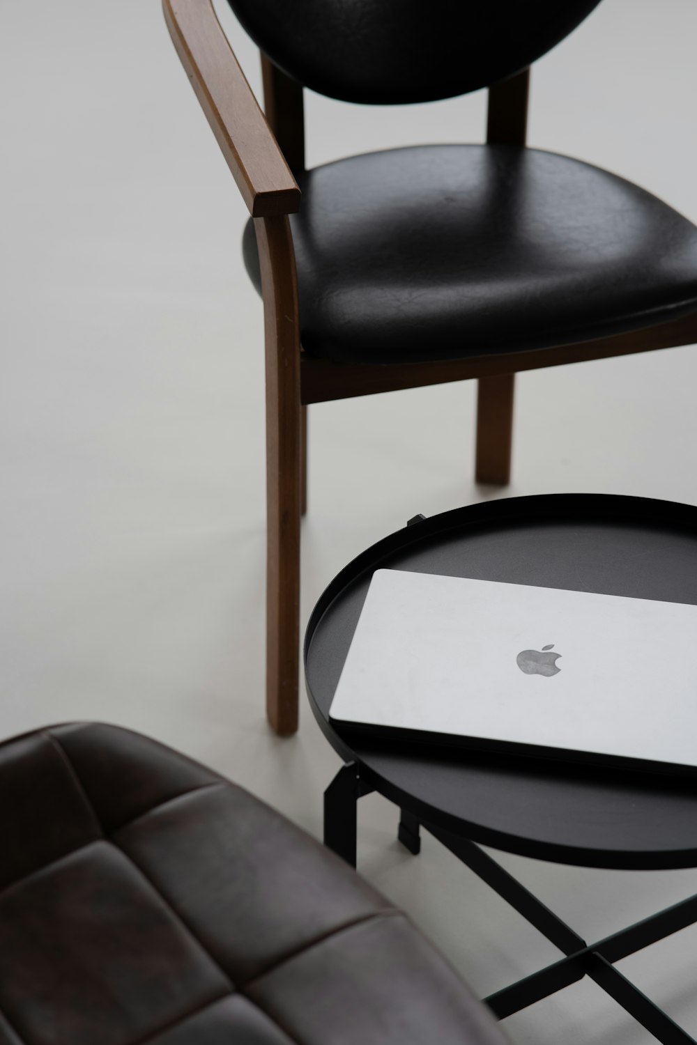 an apple laptop sitting on a table next to a chair