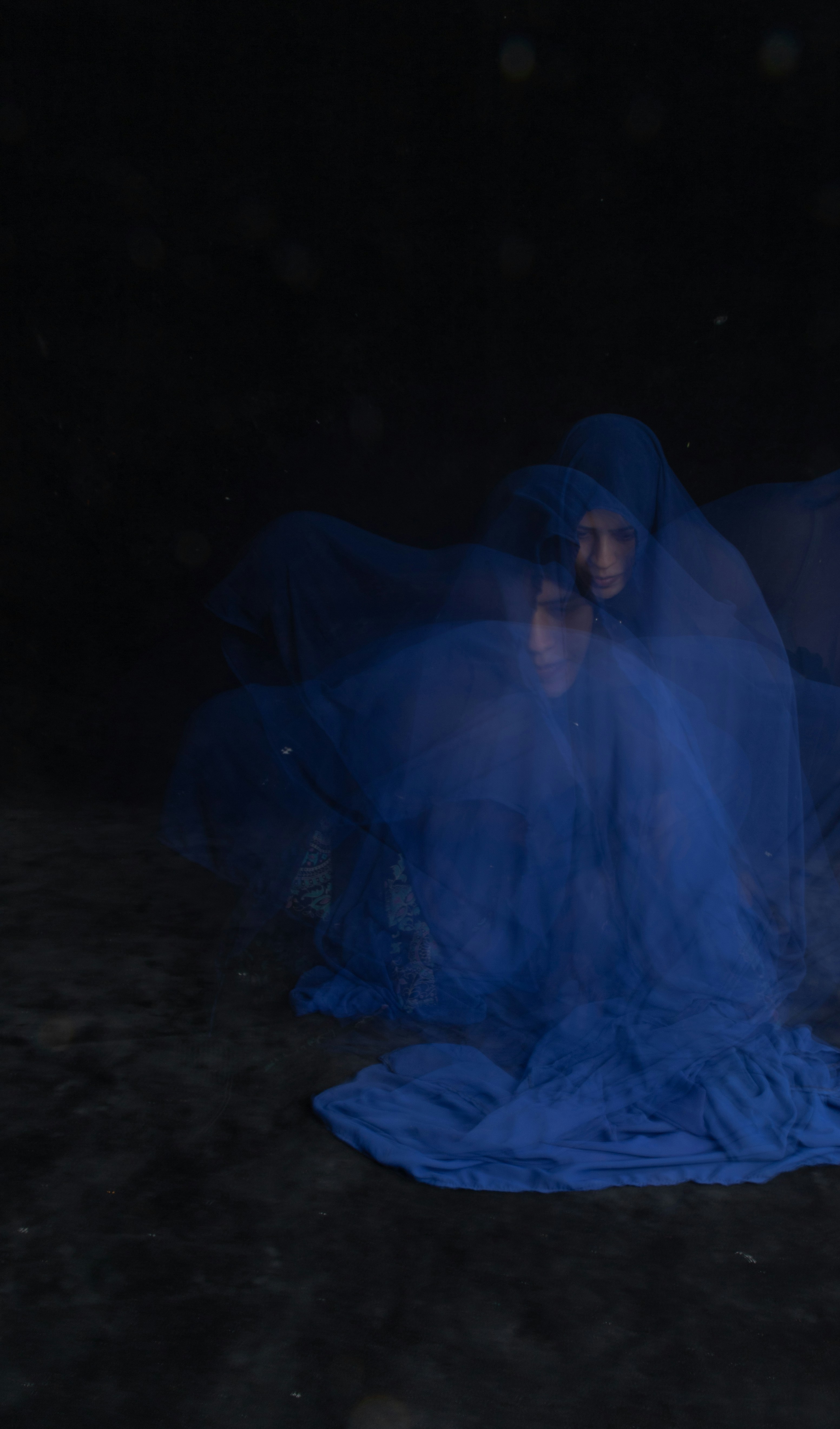 a woman in a blue dress sitting on a blanket