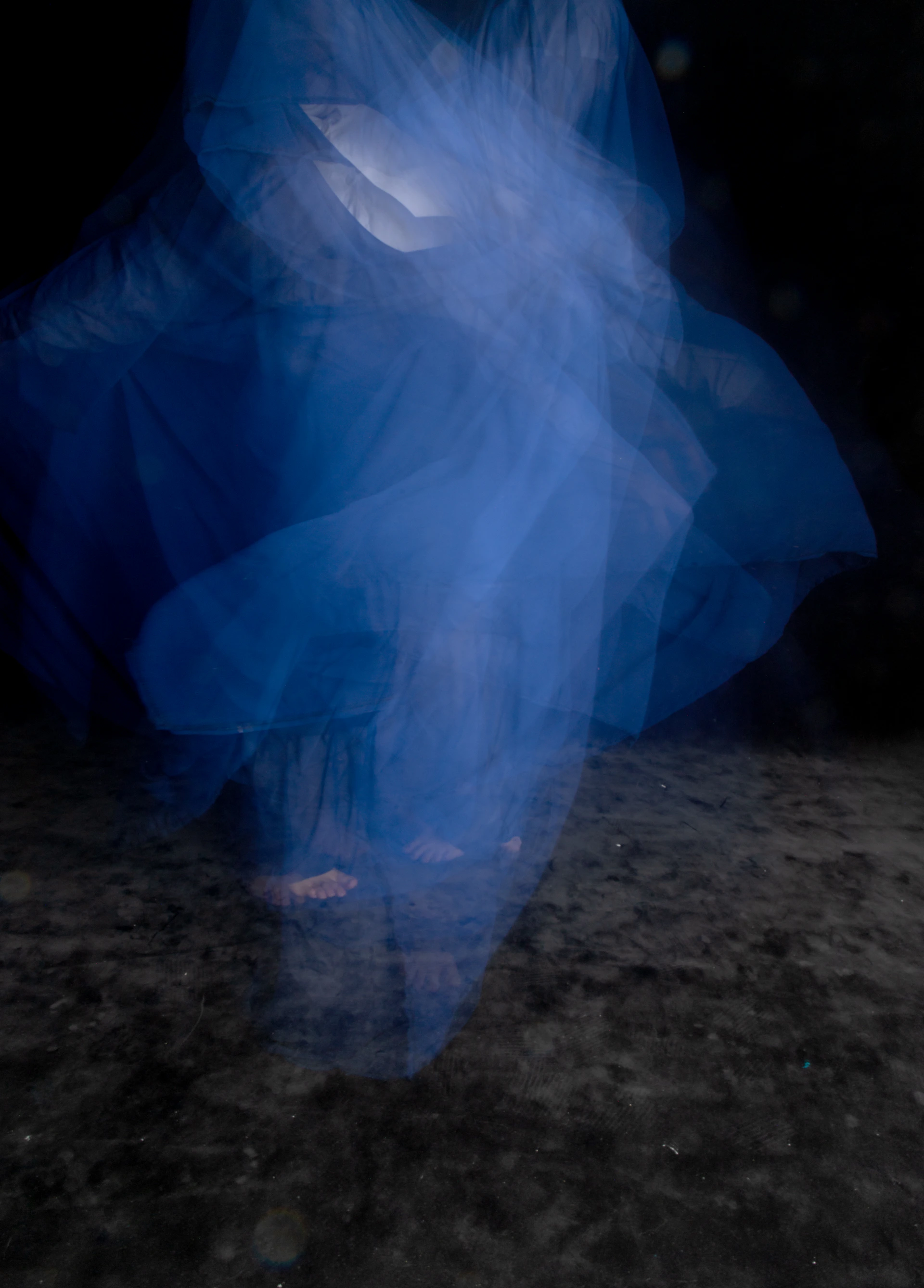 a woman in a blue dress is standing in the dark