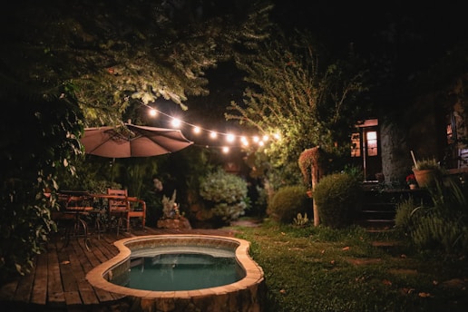 a hot tub in the middle of a garden at night