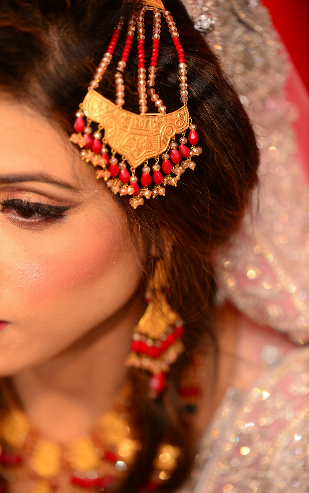 a woman wearing a red and gold necklace and earrings