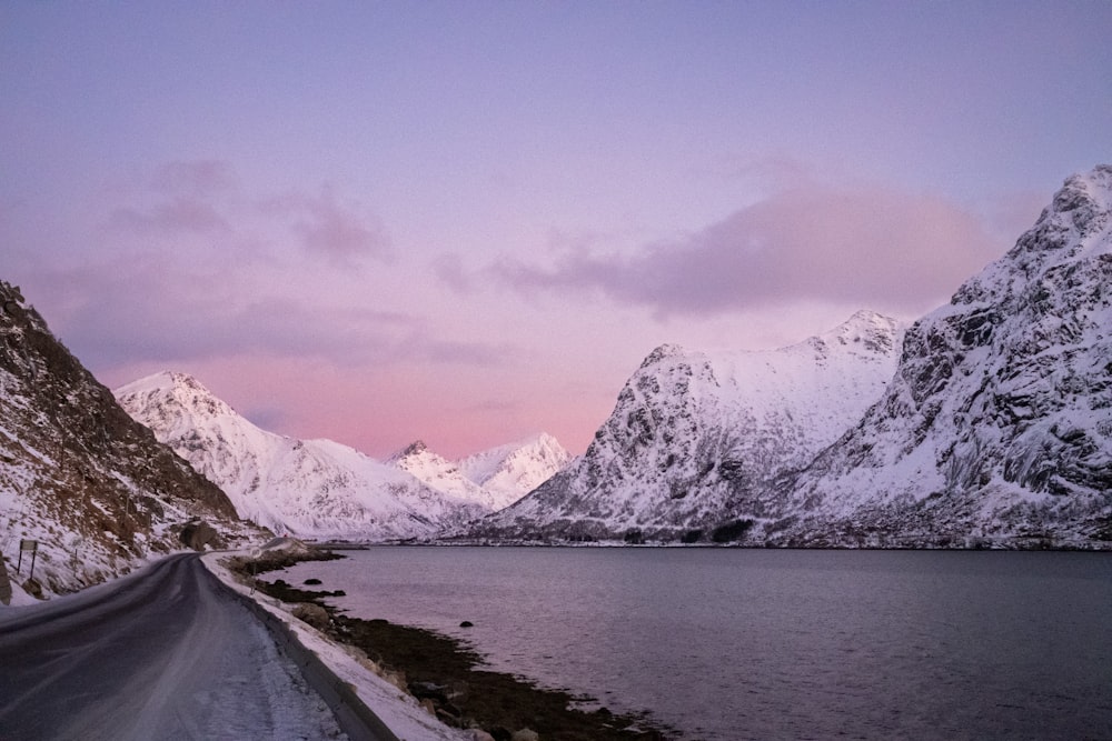 a snow covered mountain range next to a body of water