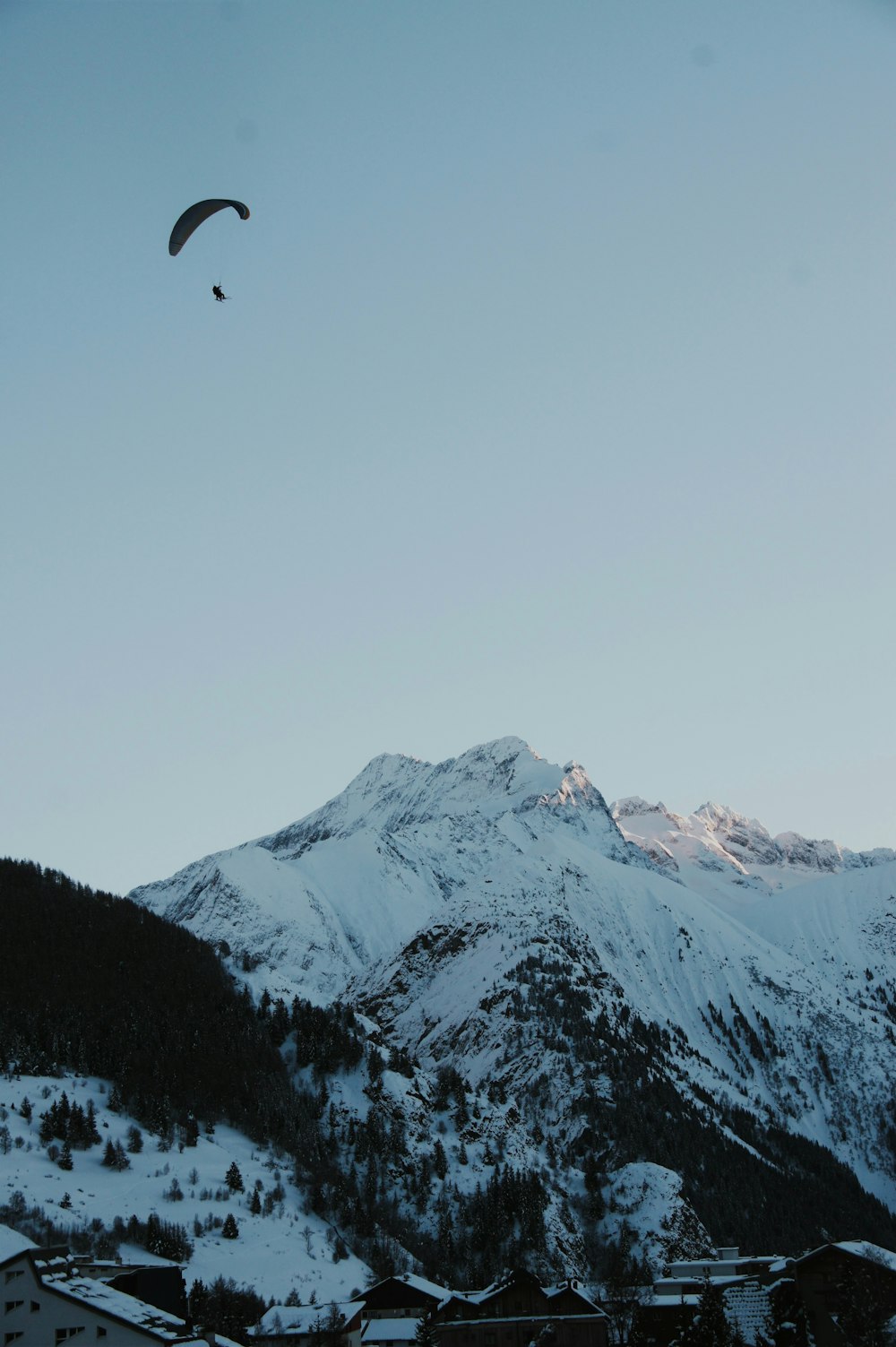 a paraglider flying over a snow covered mountain