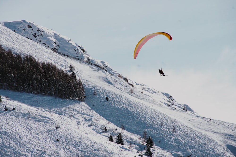 une personne fait du parachute ascensionnel sur une montagne enneigée