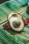 an avocado cut in half on a banana leaf