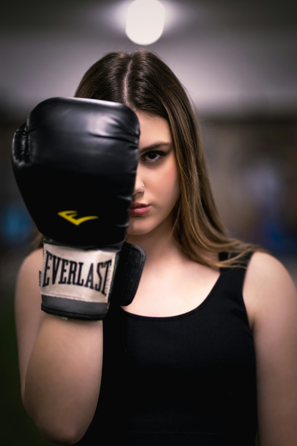 a woman wearing a black tank top and black boxing gloves