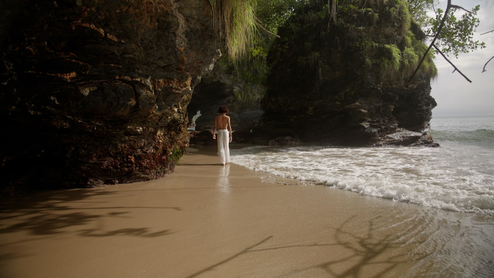a woman in a white dress walking on a beach