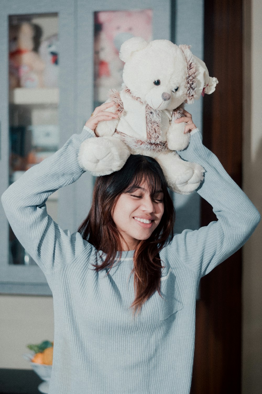 a woman holding a teddy bear on her head