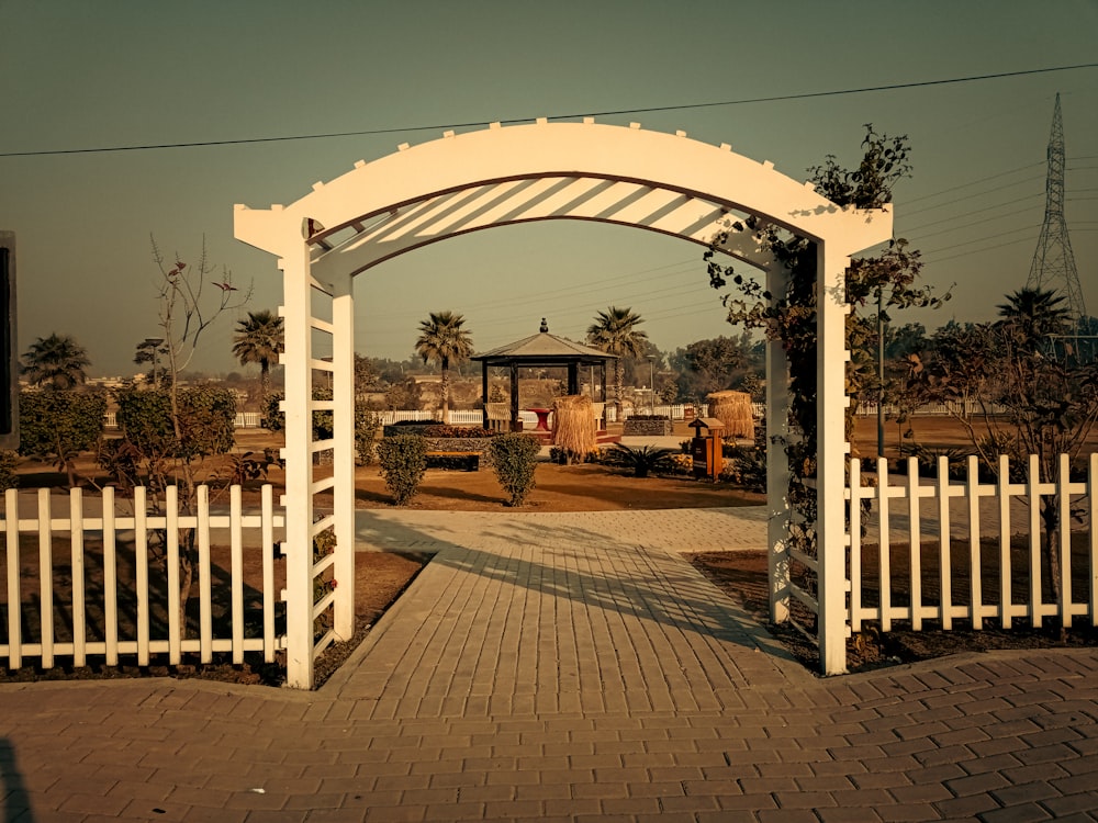 a white gate with a brick walkway leading to it