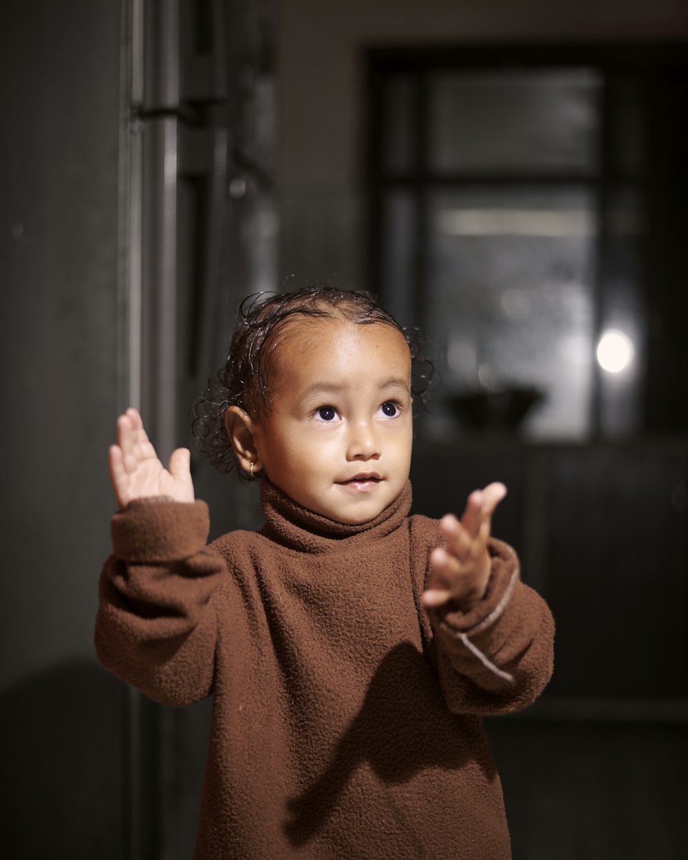 a little girl standing in a room with her hands in the air