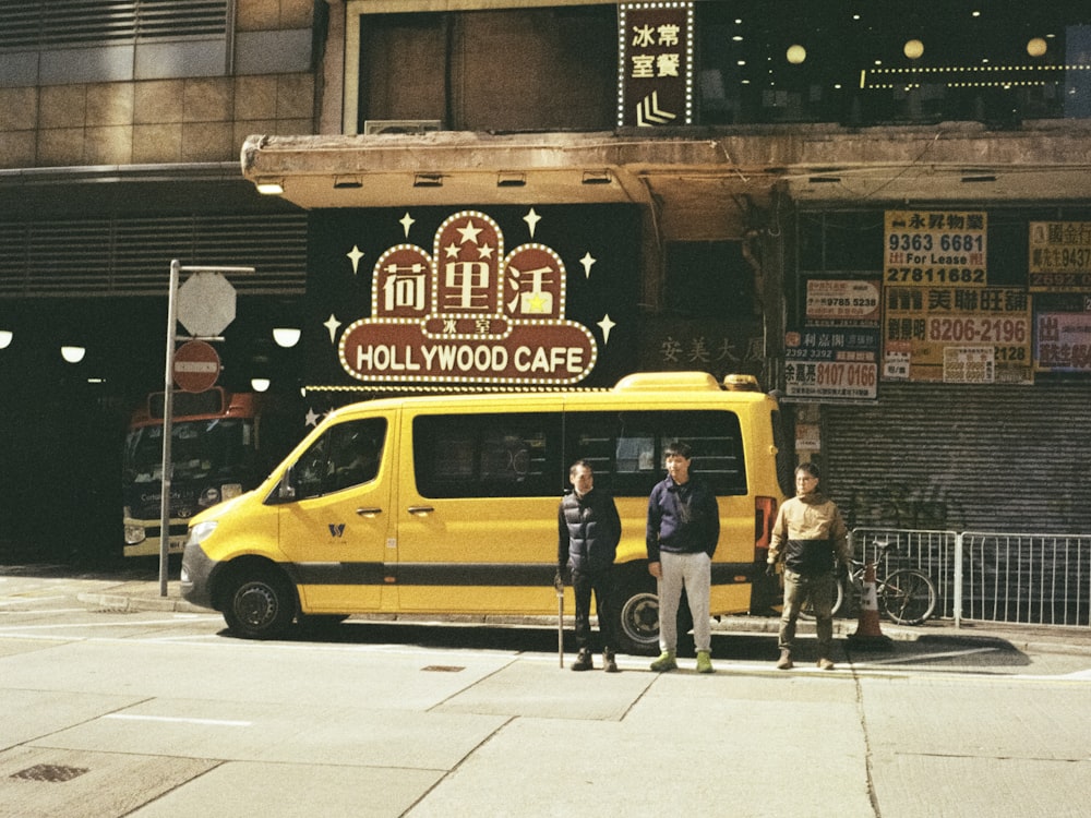 three men standing in front of a yellow van
