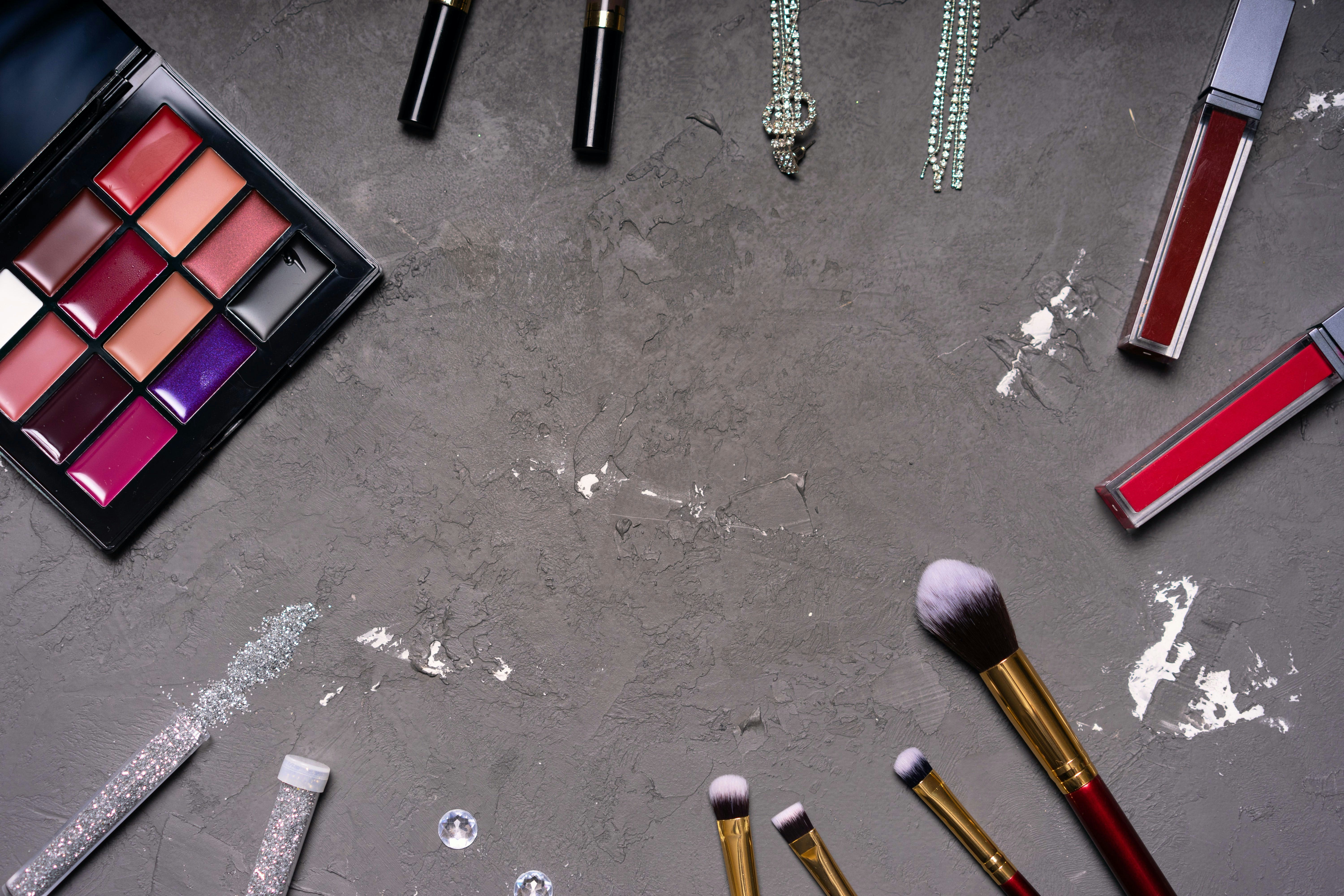 Premium makeup collection flat lay on dark background with elegant minimal styling