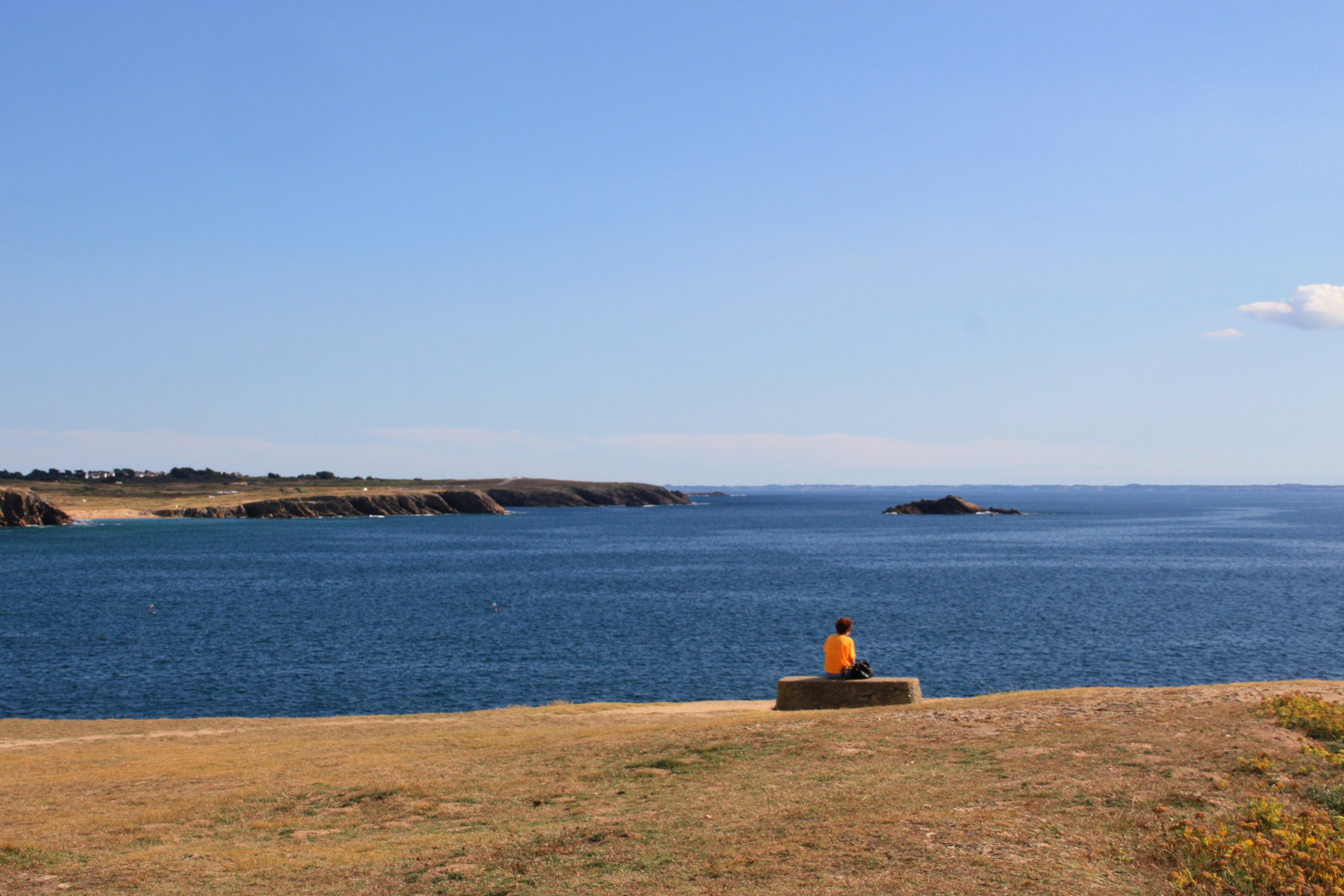 a person sitting on a bench looking out at the ocean