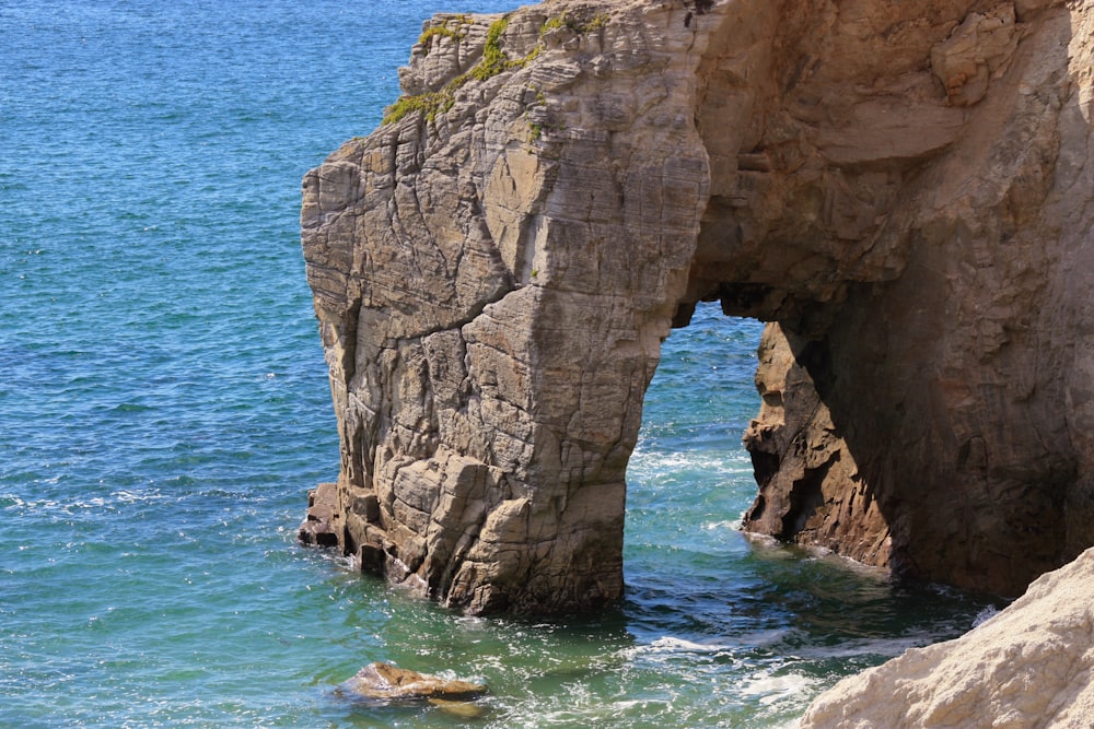 a large rock formation in the ocean near a beach