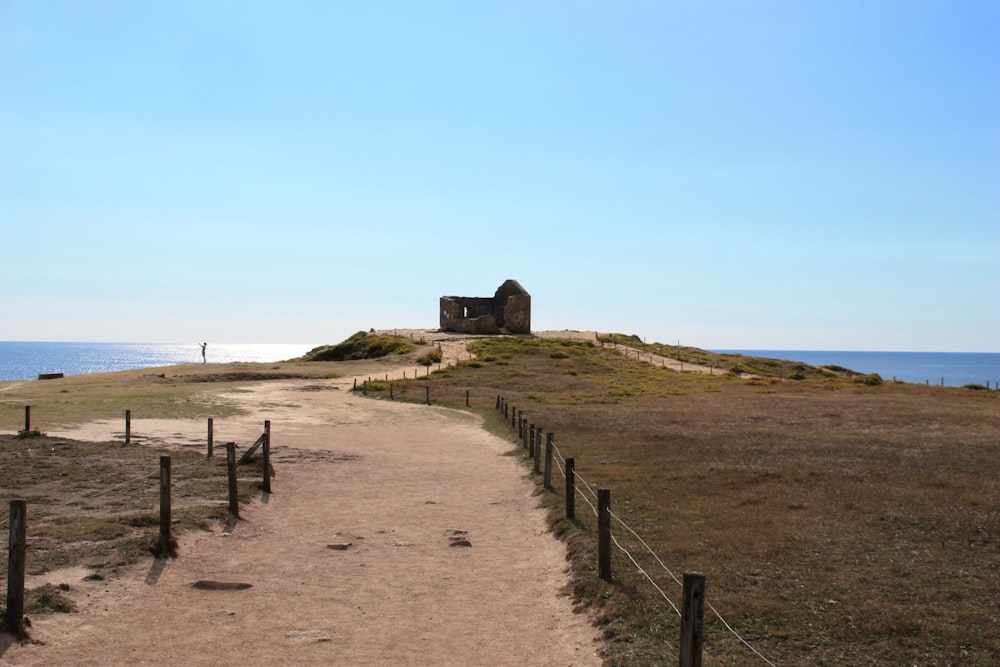 a dirt path leading to an old building on a beach