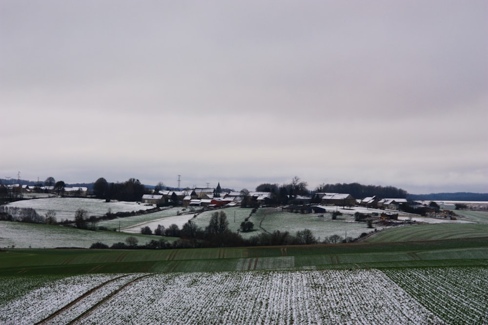 a snow covered field with a small town in the distance