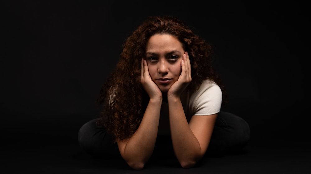 a woman sitting on the floor with her hands on her face