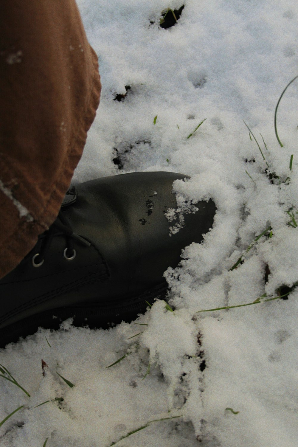 a person standing in the snow wearing black boots