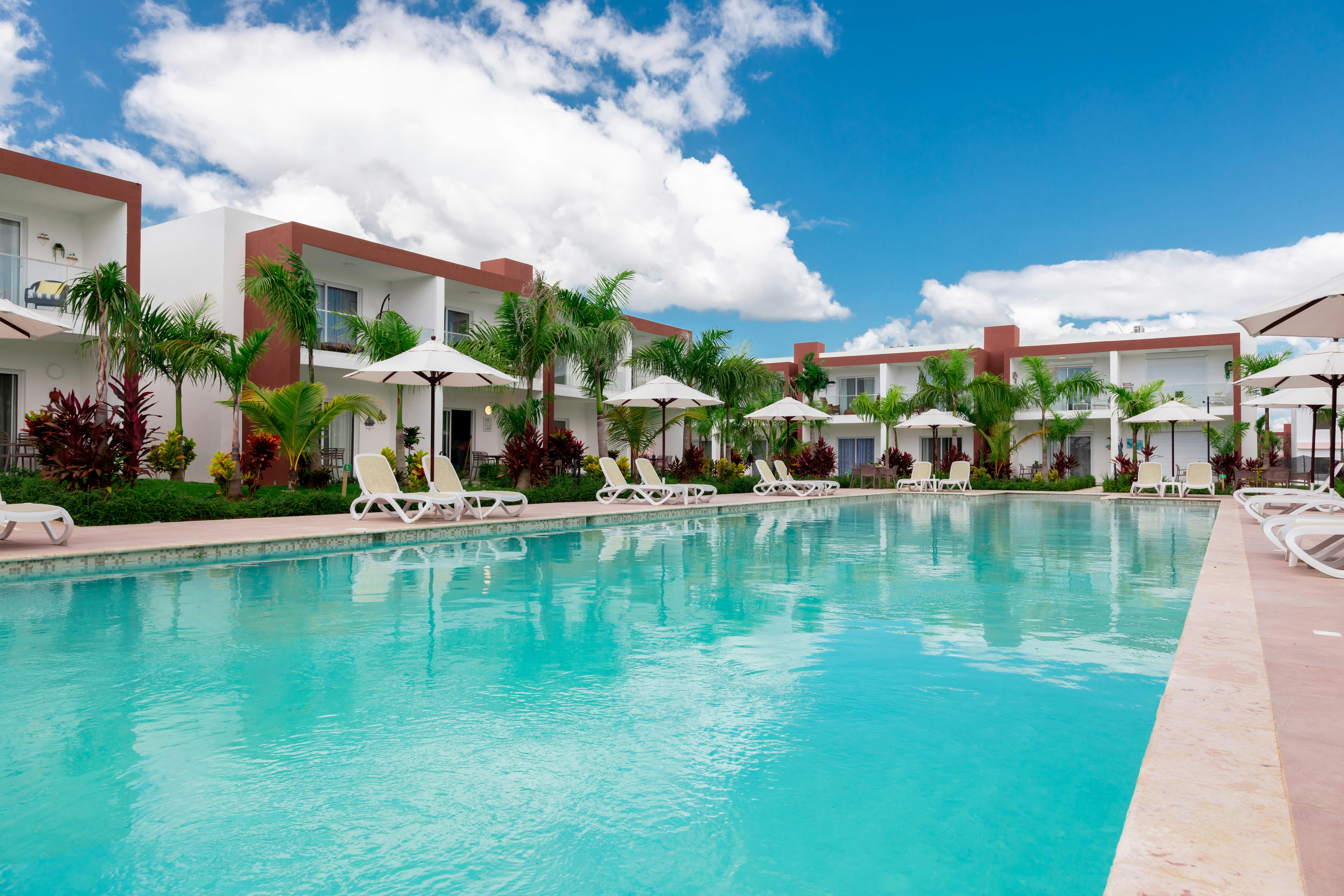 a large swimming pool surrounded by lawn chairs and umbrellas