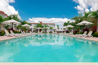a large swimming pool surrounded by lawn chairs and umbrellas