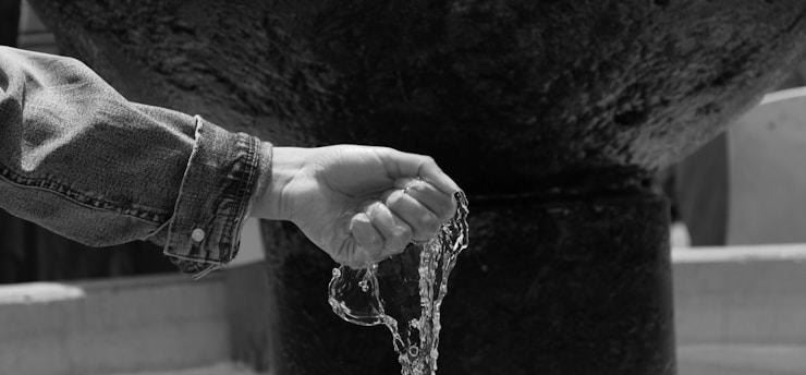 a person's hand holding water from a fountain