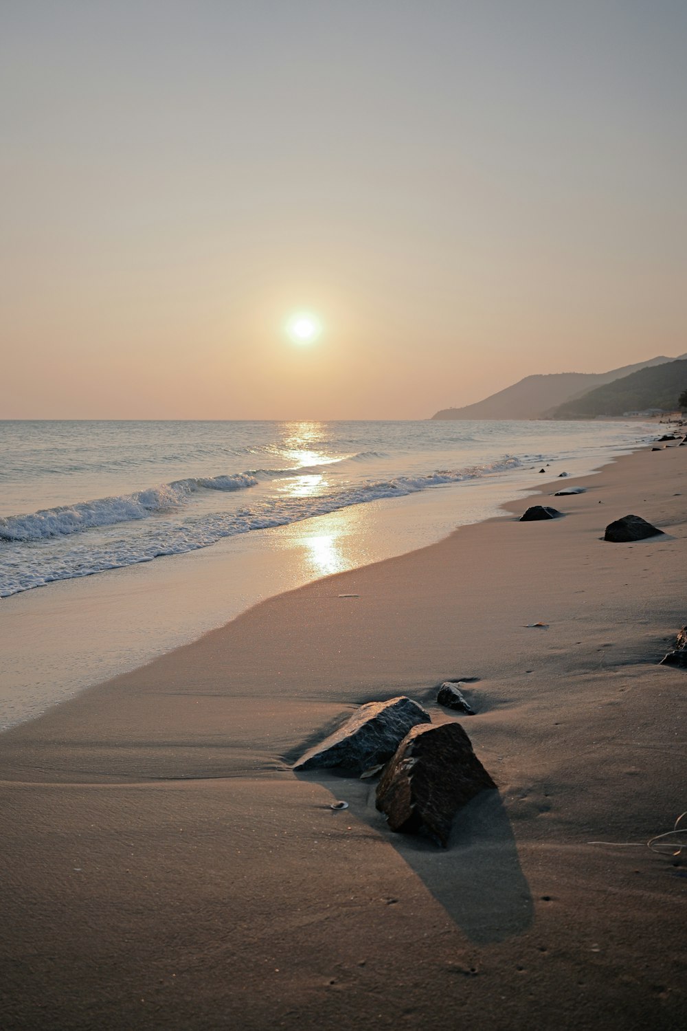 the sun is setting over the ocean on the beach