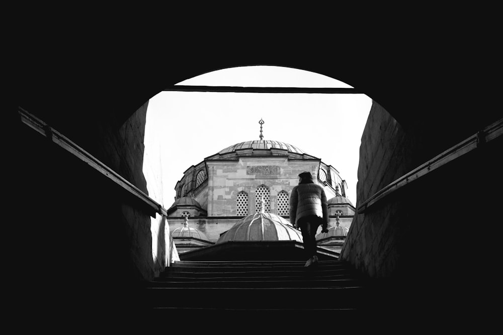 a black and white photo of a person walking up some stairs