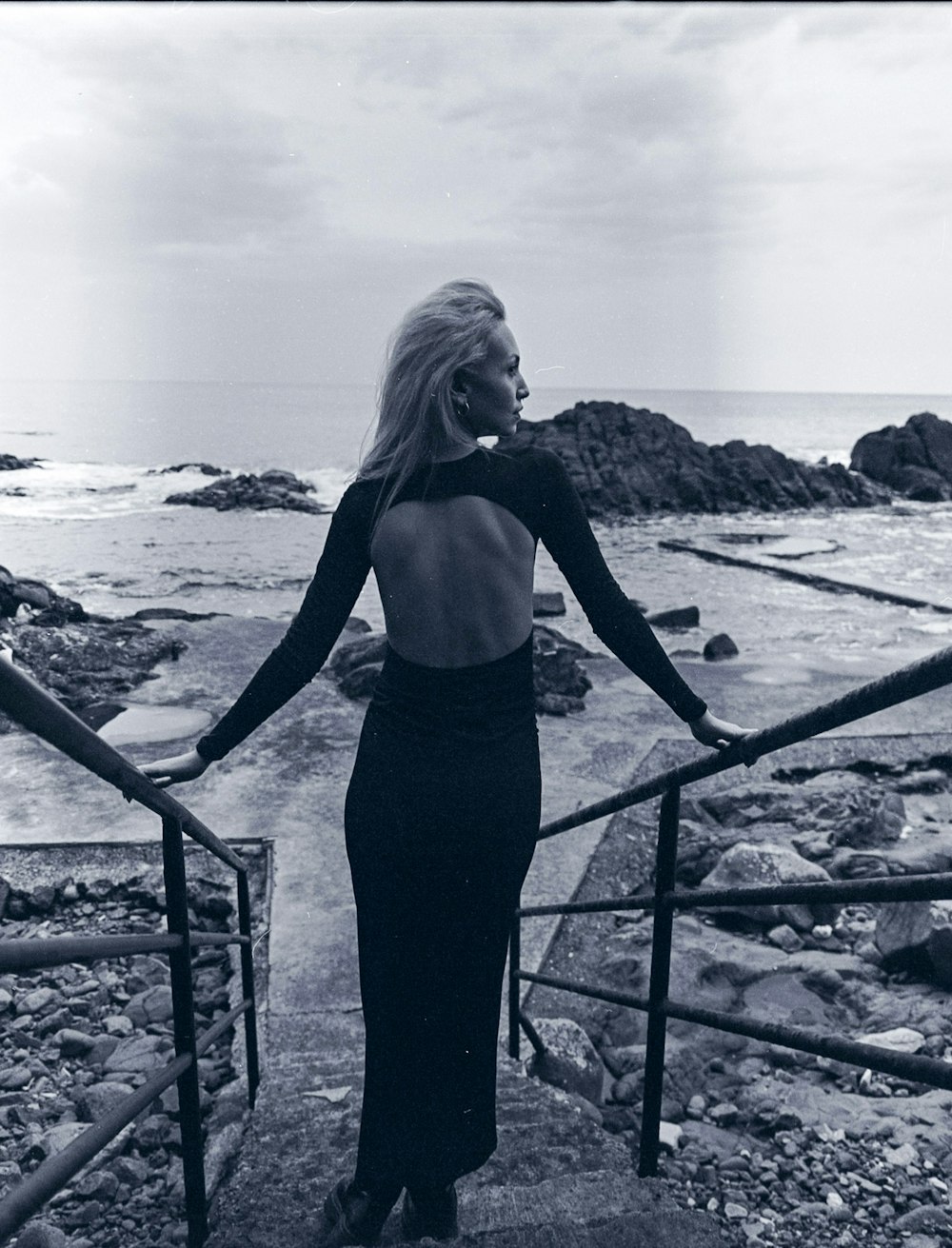 a woman in a long black dress standing on a railing