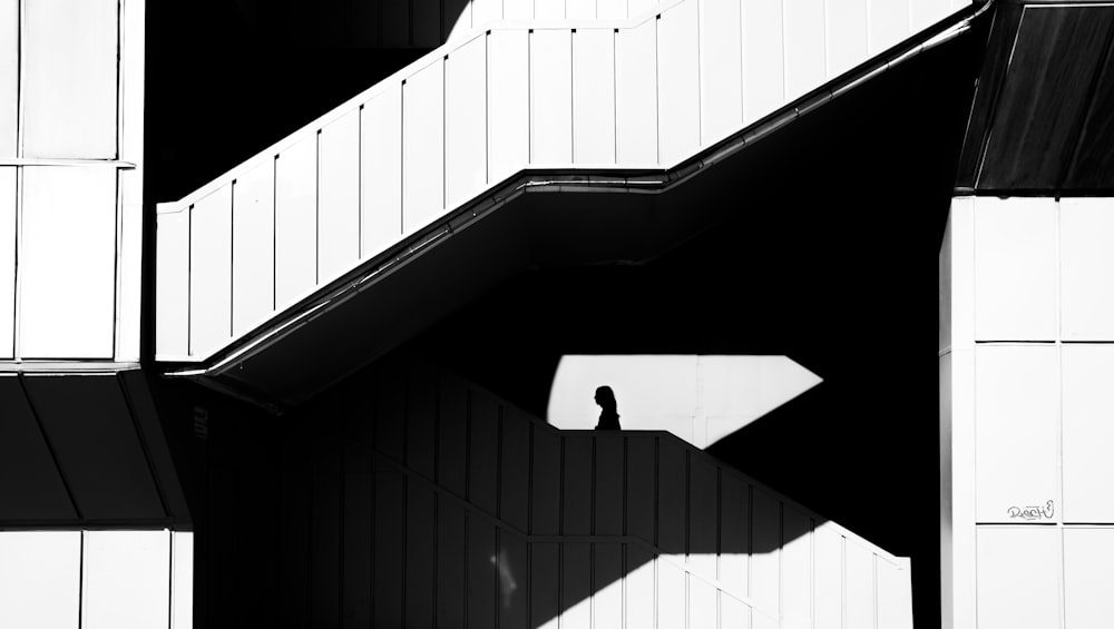 a black and white photo of a person standing under a staircase