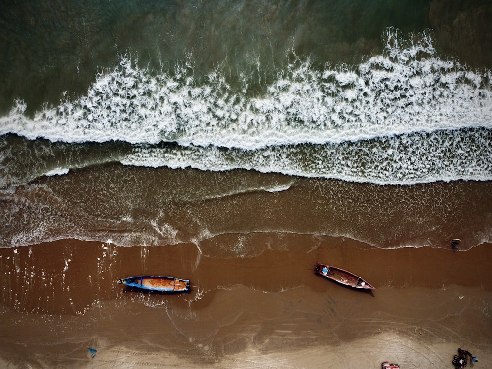 two small boats on a beach near the ocean