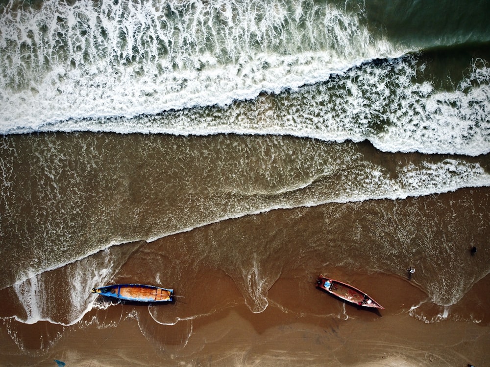 due barche sedute in cima a una spiaggia vicino all'oceano