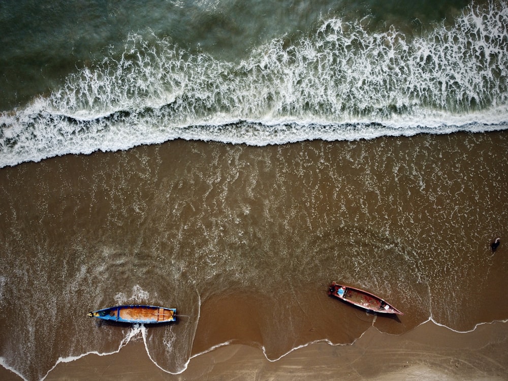 two small boats sitting on top of a sandy beach