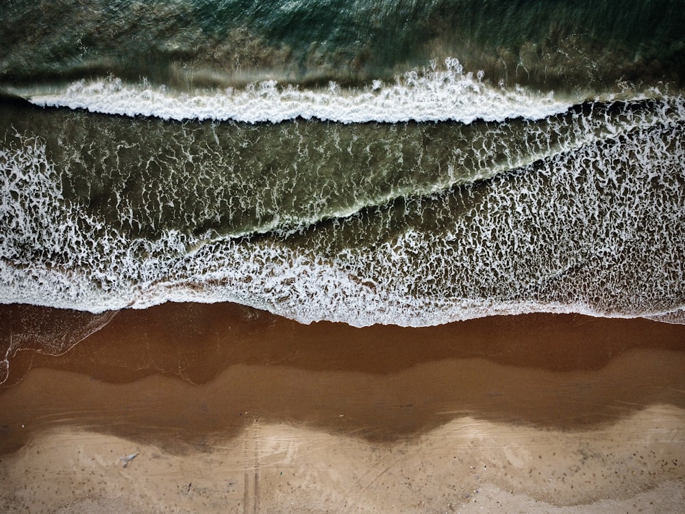 an aerial view of a beach with waves and sand