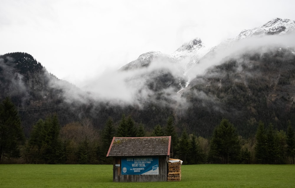 a small building in a field with mountains in the background