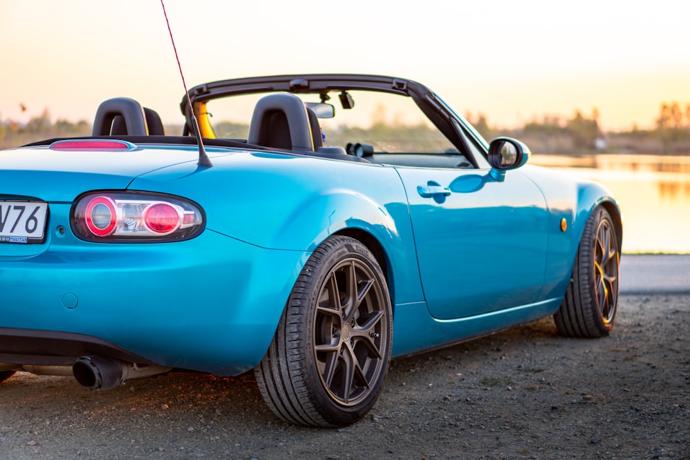 a blue sports car parked next to a body of water