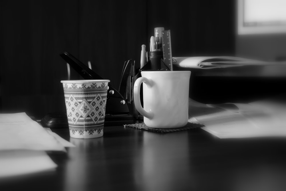 a black and white photo of a desk with a cup of coffee