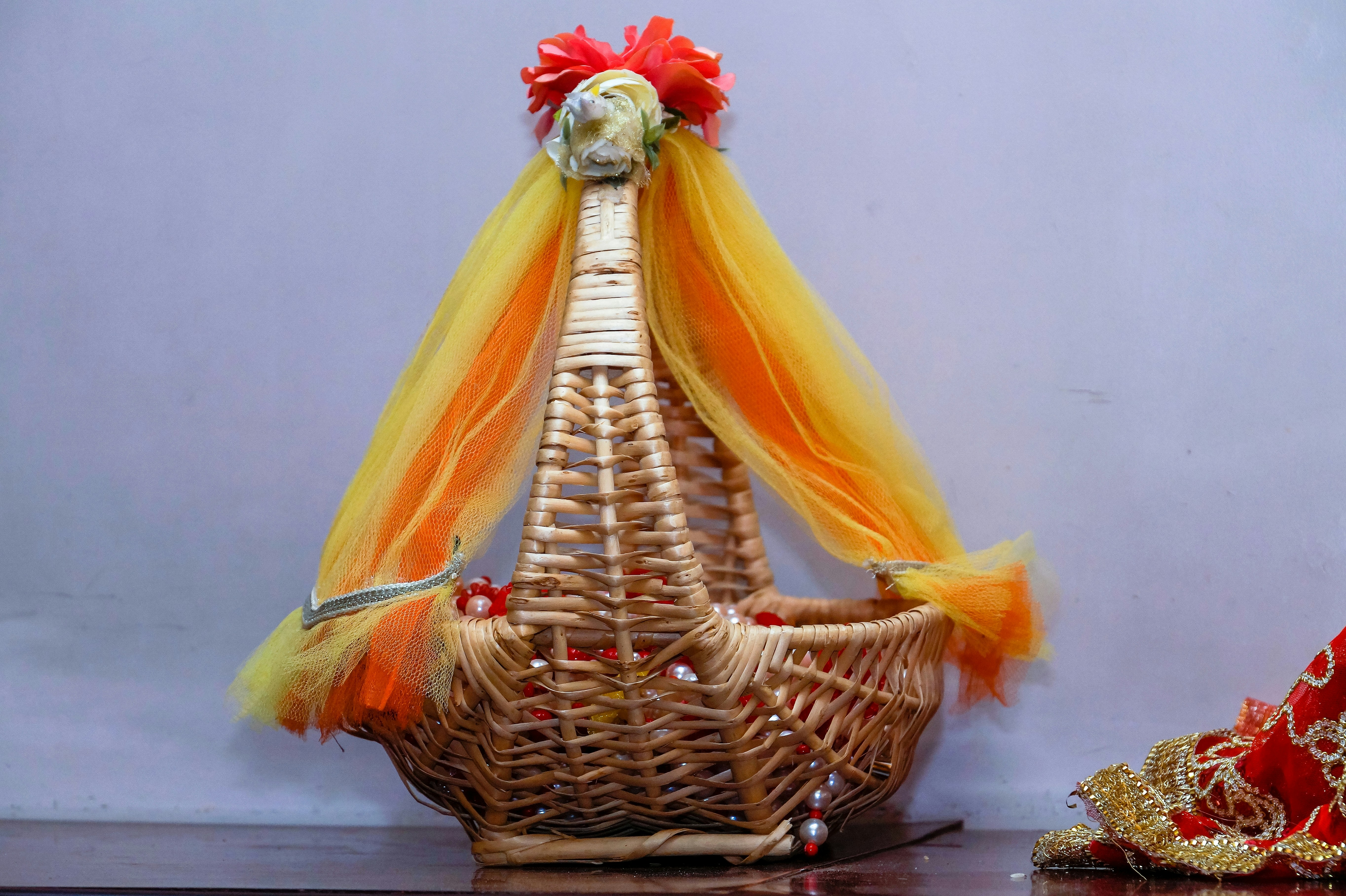Warm autumnal flower mix with orange, red, and gold tones in a woven basket