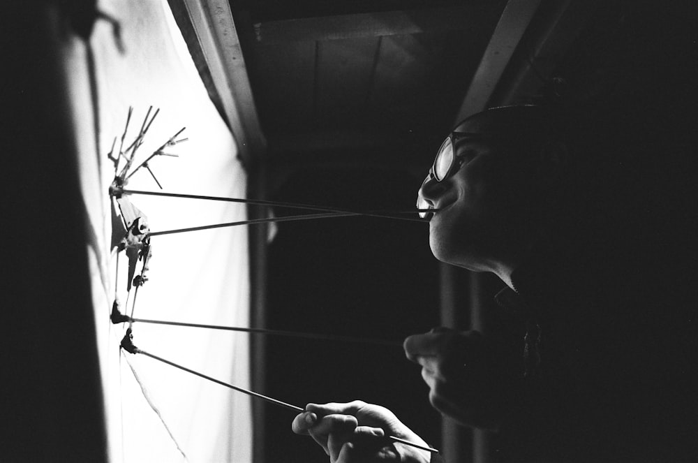 a woman holding a bunch of sticks in front of a window
