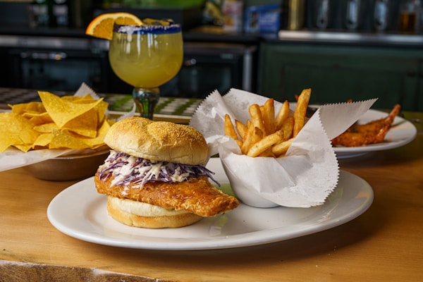 A chicken sandwich with coleslaw and chips on a plate