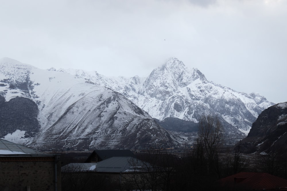 a snow covered mountain range with houses in the foreground