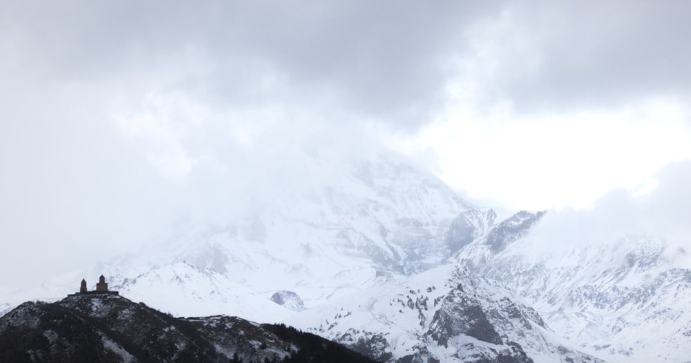 a couple of people standing on top of a snow covered mountain