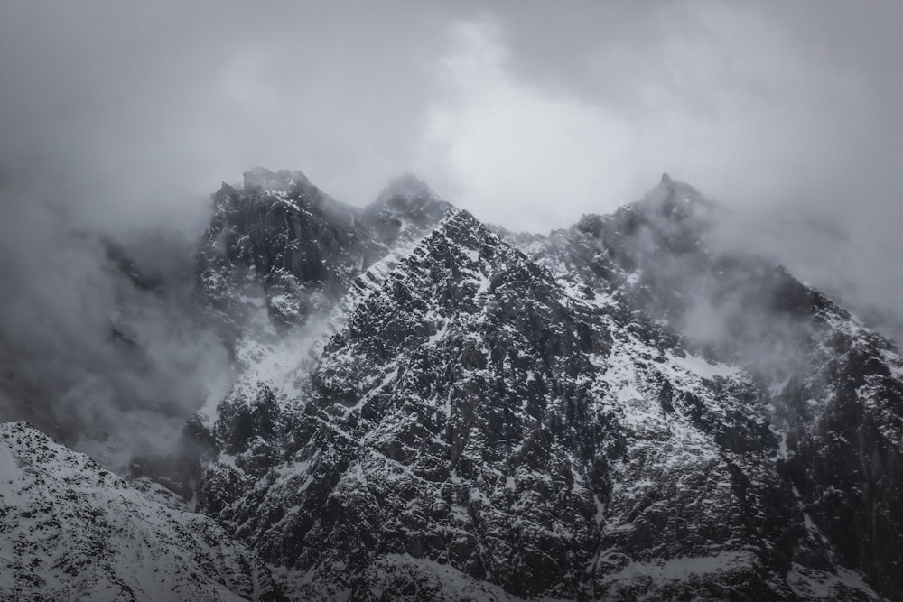 a very tall mountain covered in snow under a cloudy sky