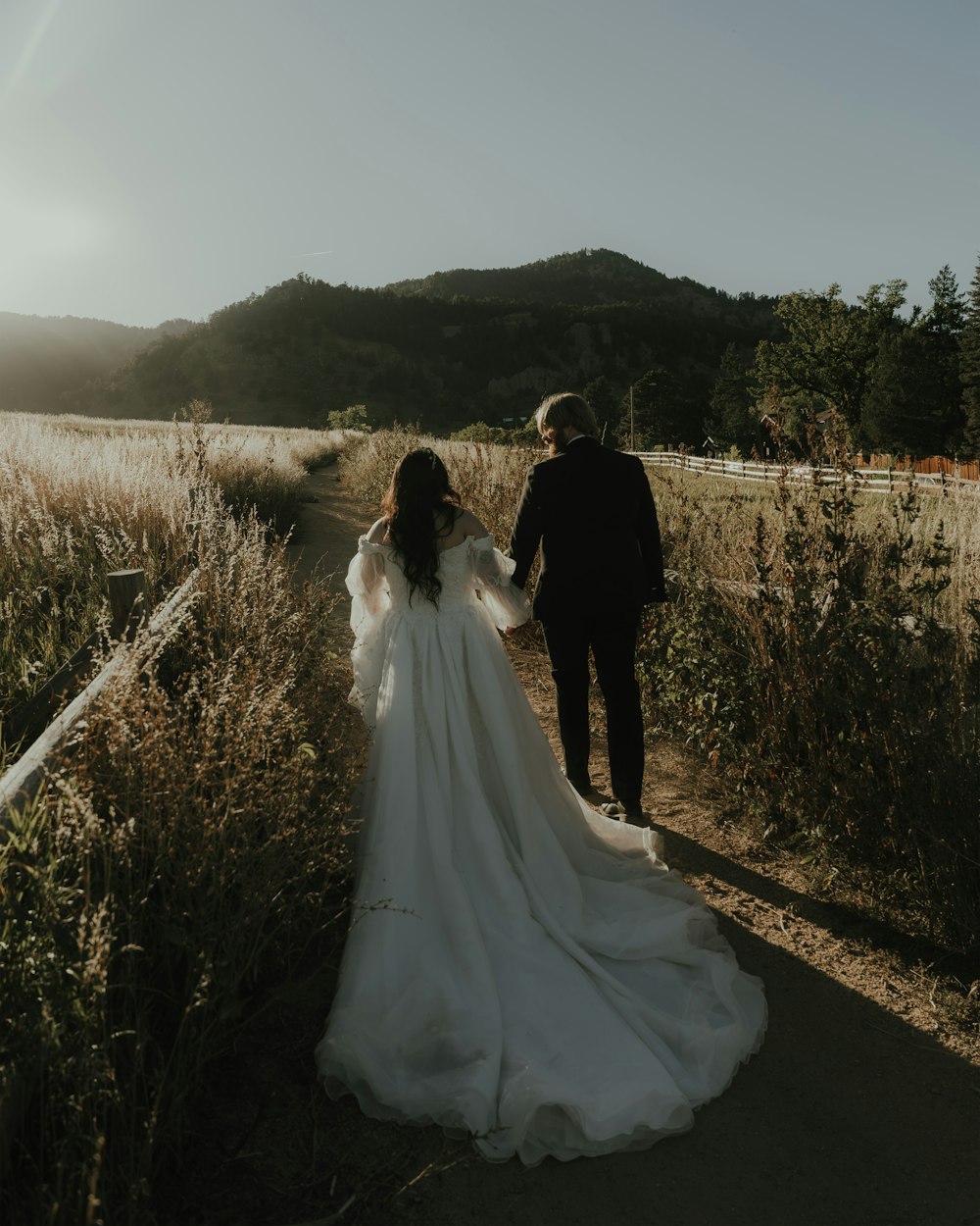 a bride and groom walking through a field