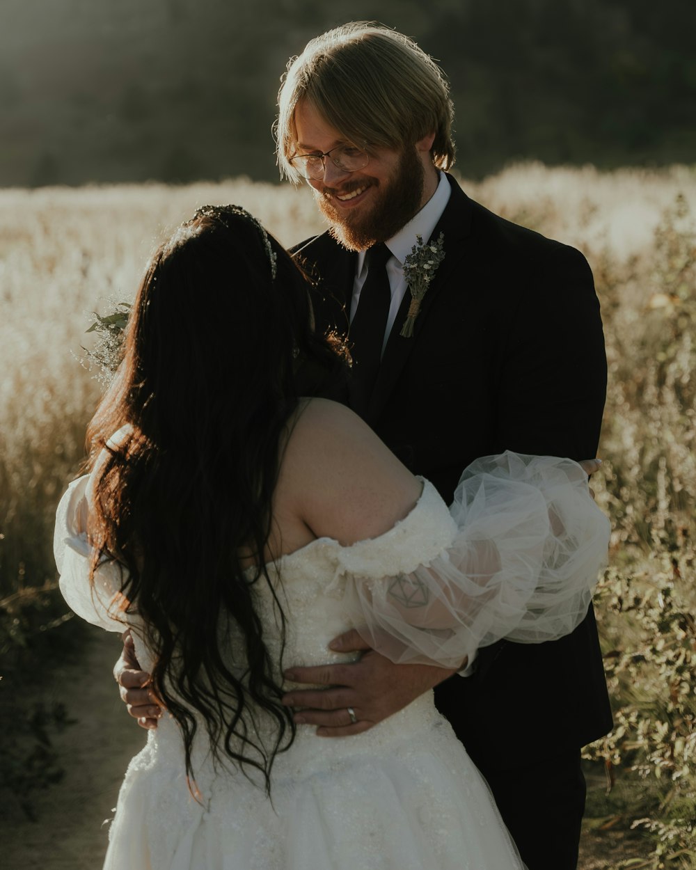 a bride and groom hugging in a field