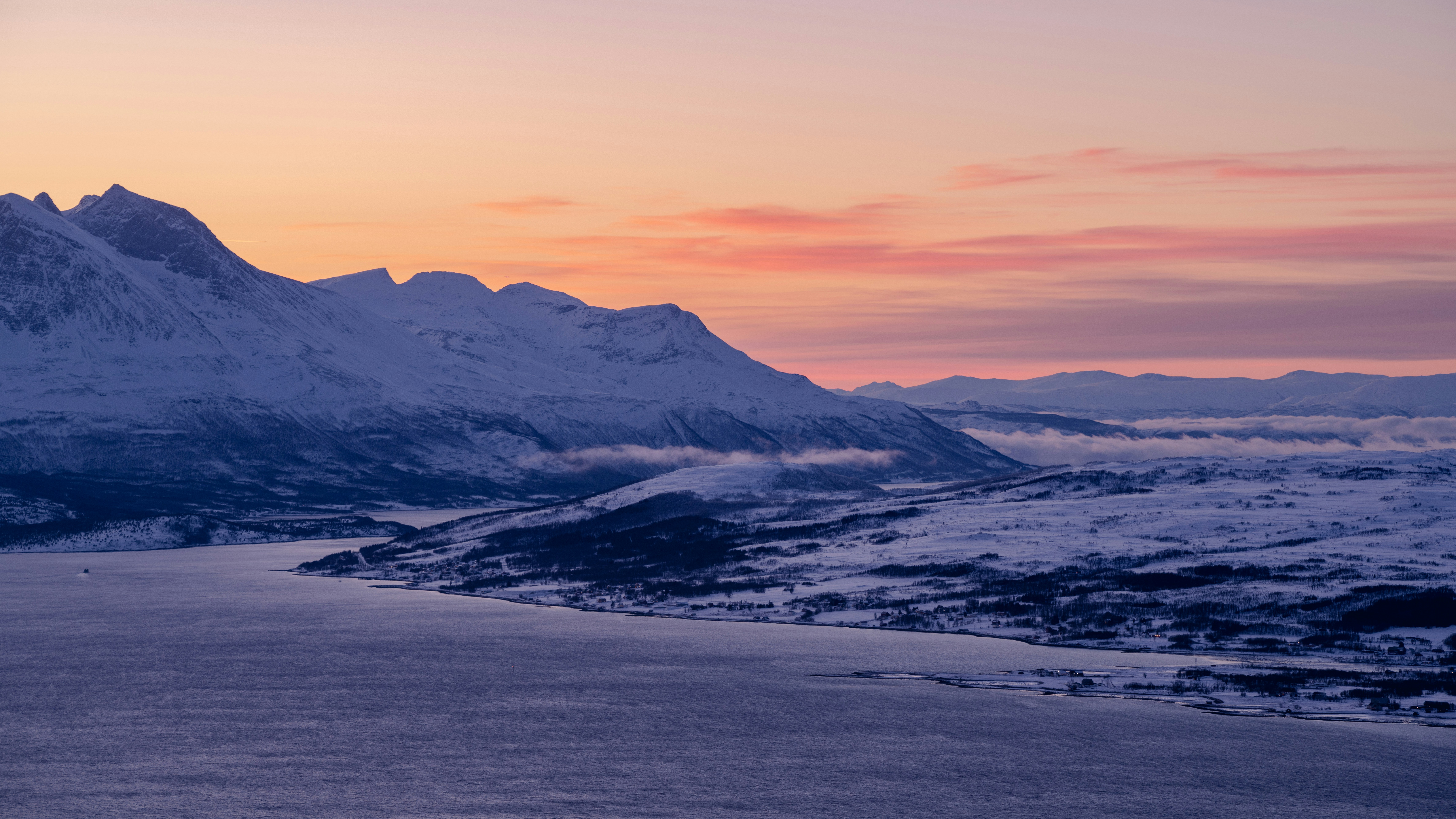 a snow covered mountain with a lake in the foreground, Fjords, mountains, and barren arctic lands in polar twilight around Tromso, Norway.