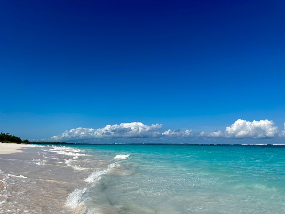 a sandy beach with clear blue water under a blue sky