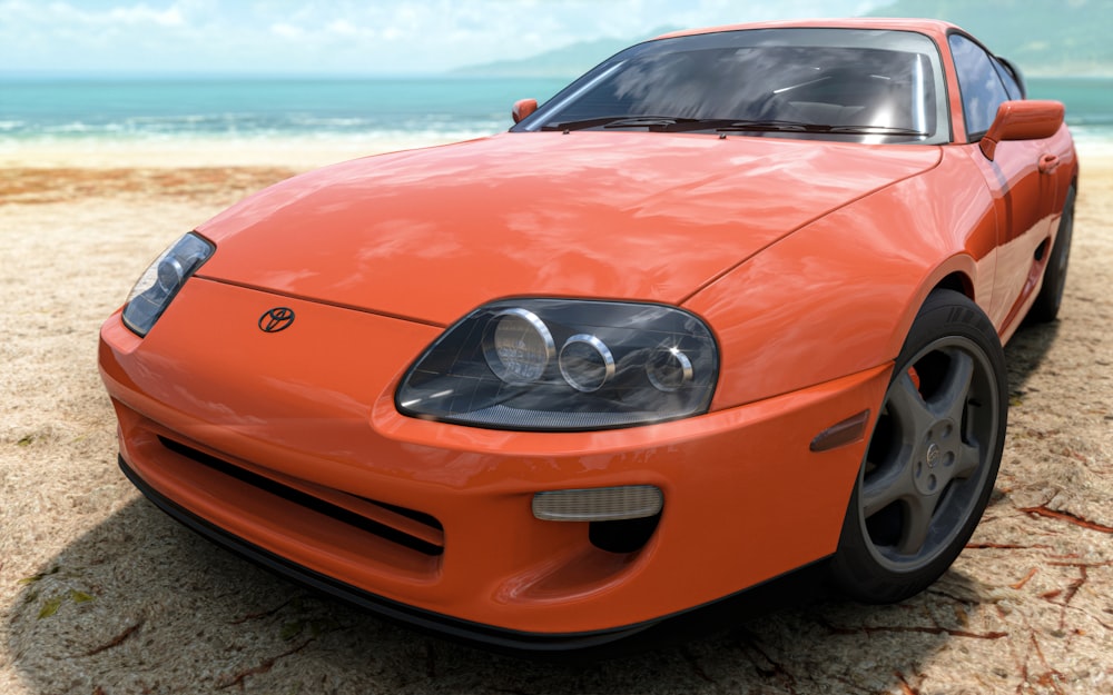an orange sports car parked on a sandy beach